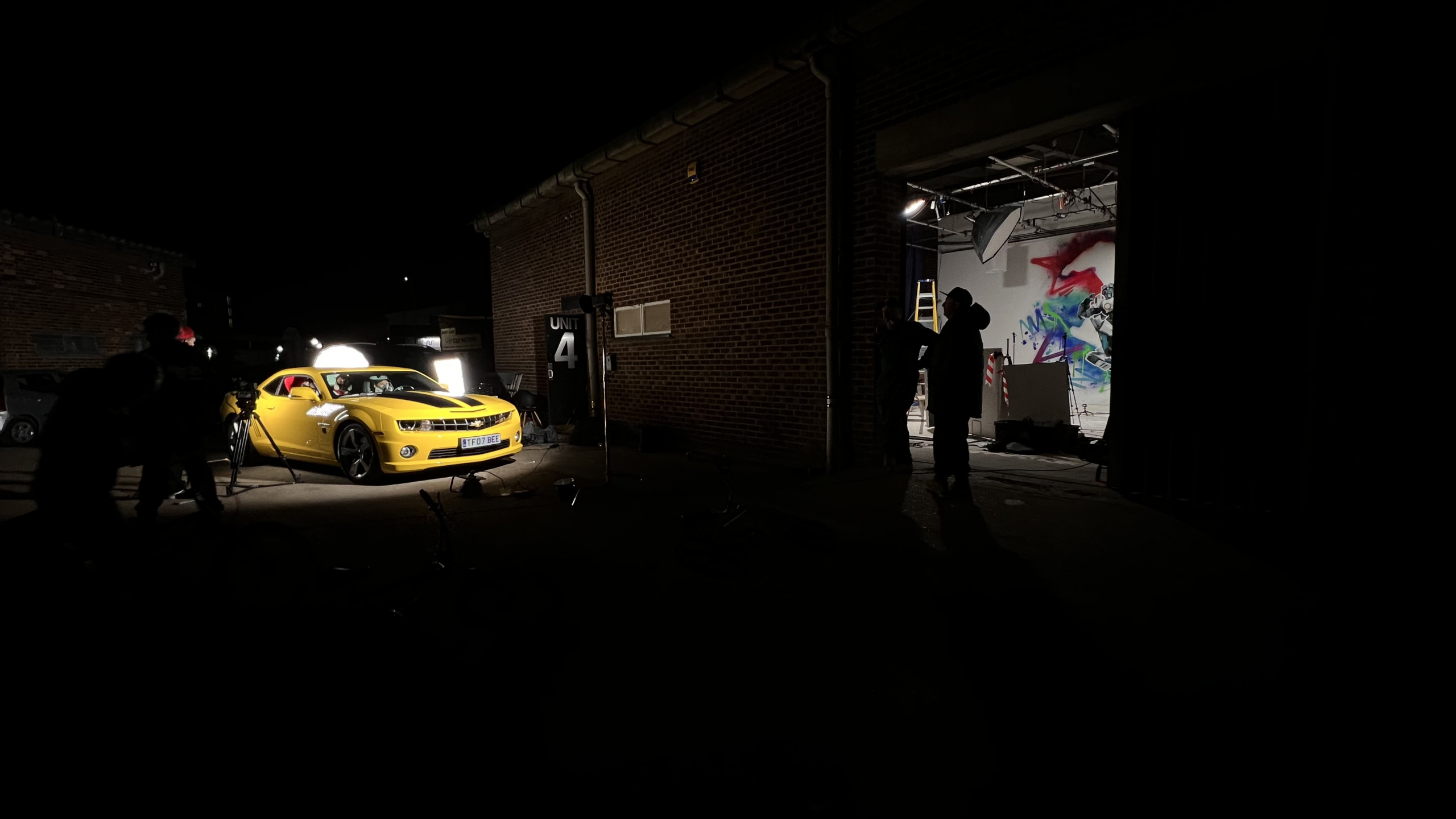Yellow Camaro and crew outside the open studio shutter during a night shoot