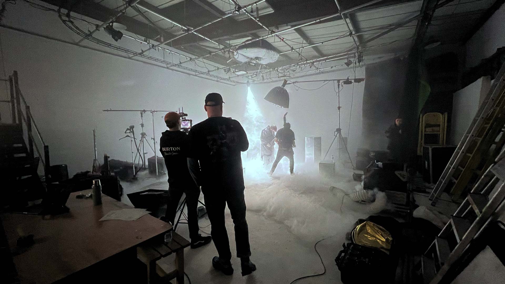 Film Studio Location with an Infinity Cove where a bright spot light is on a guitarist while a cameraman films him