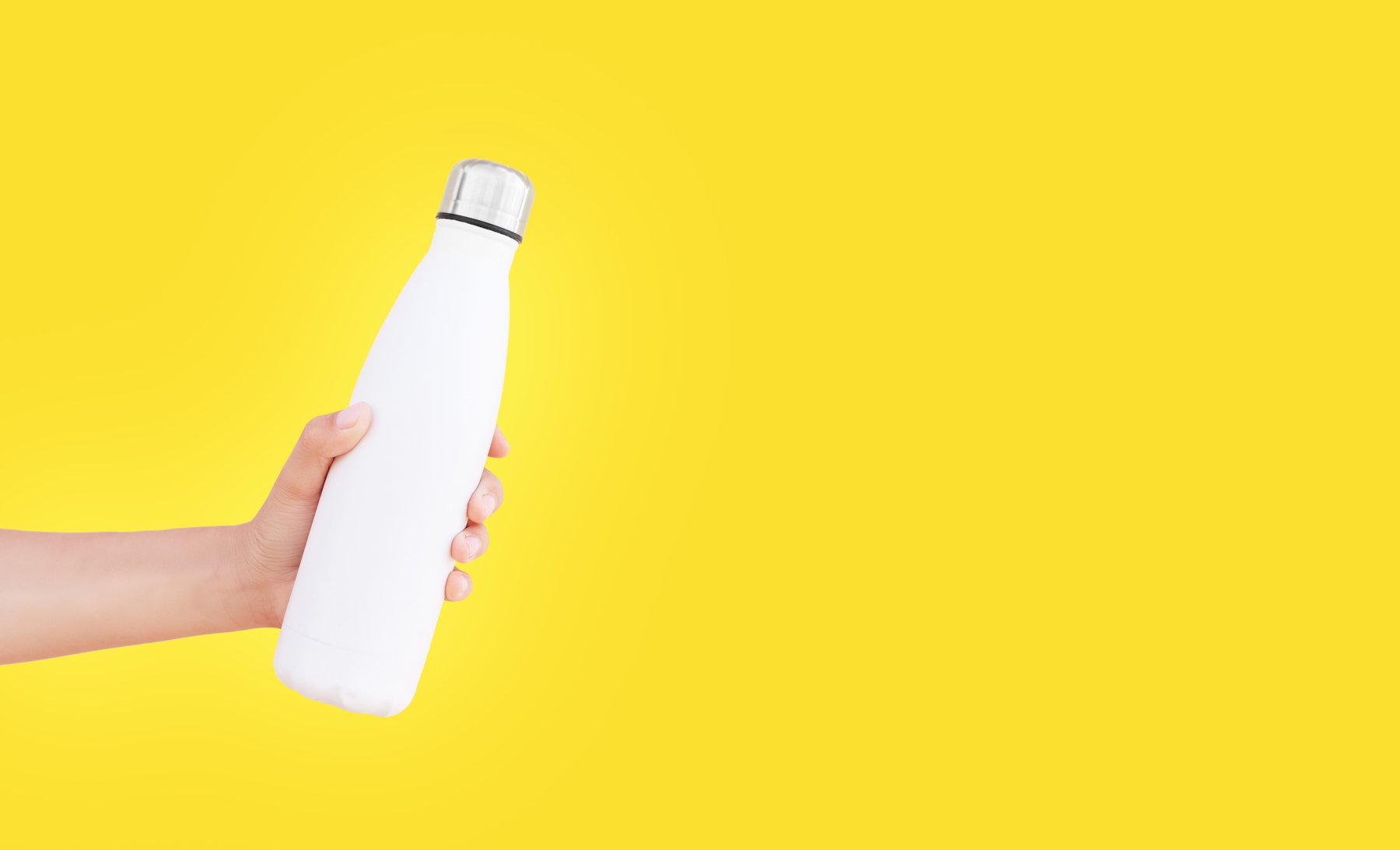 Hand holding a reusable bottle against yellow