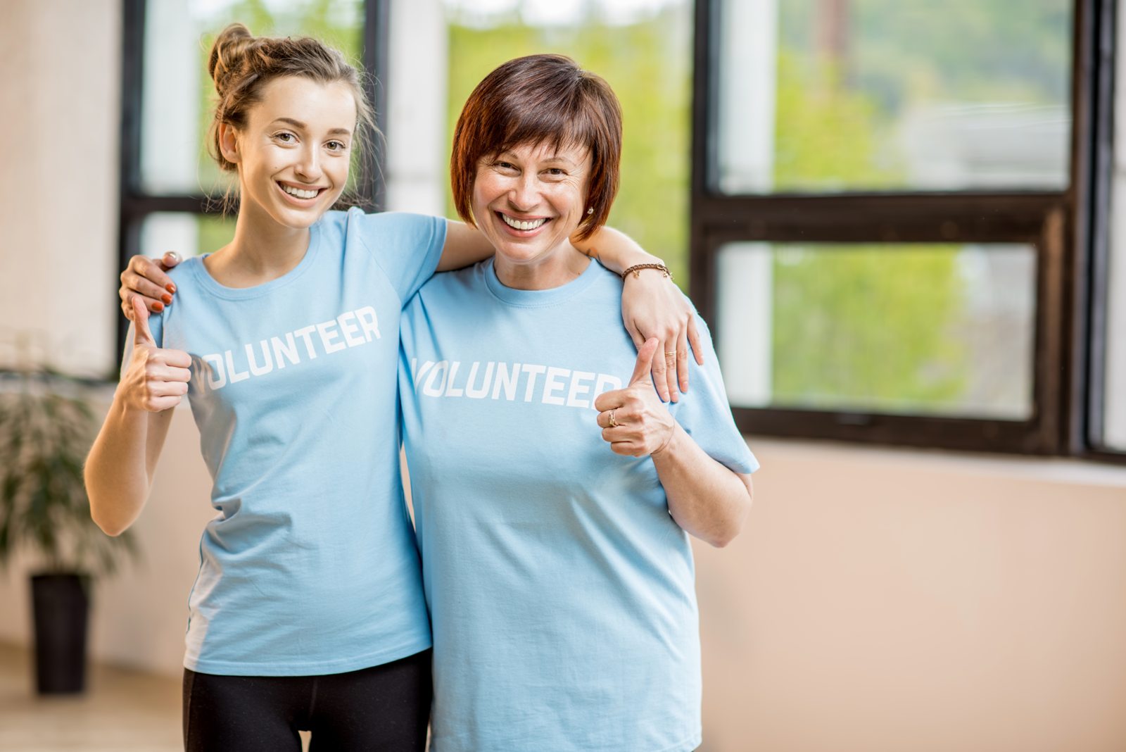 Two volunteers smiling together in blue volunteer shirts