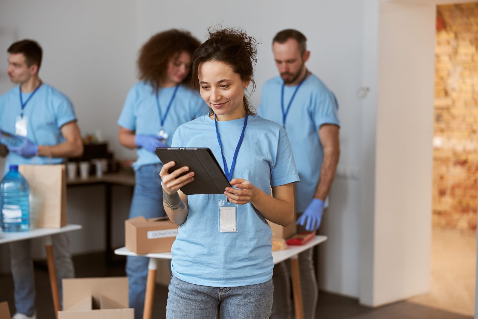 Volunteer using a tablet while a team organises donated supplies