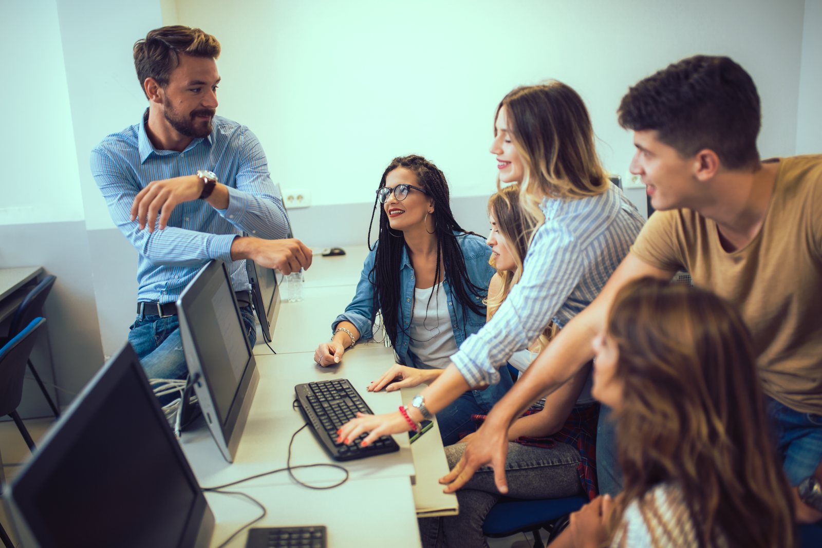 Tutor assisting students working at computers