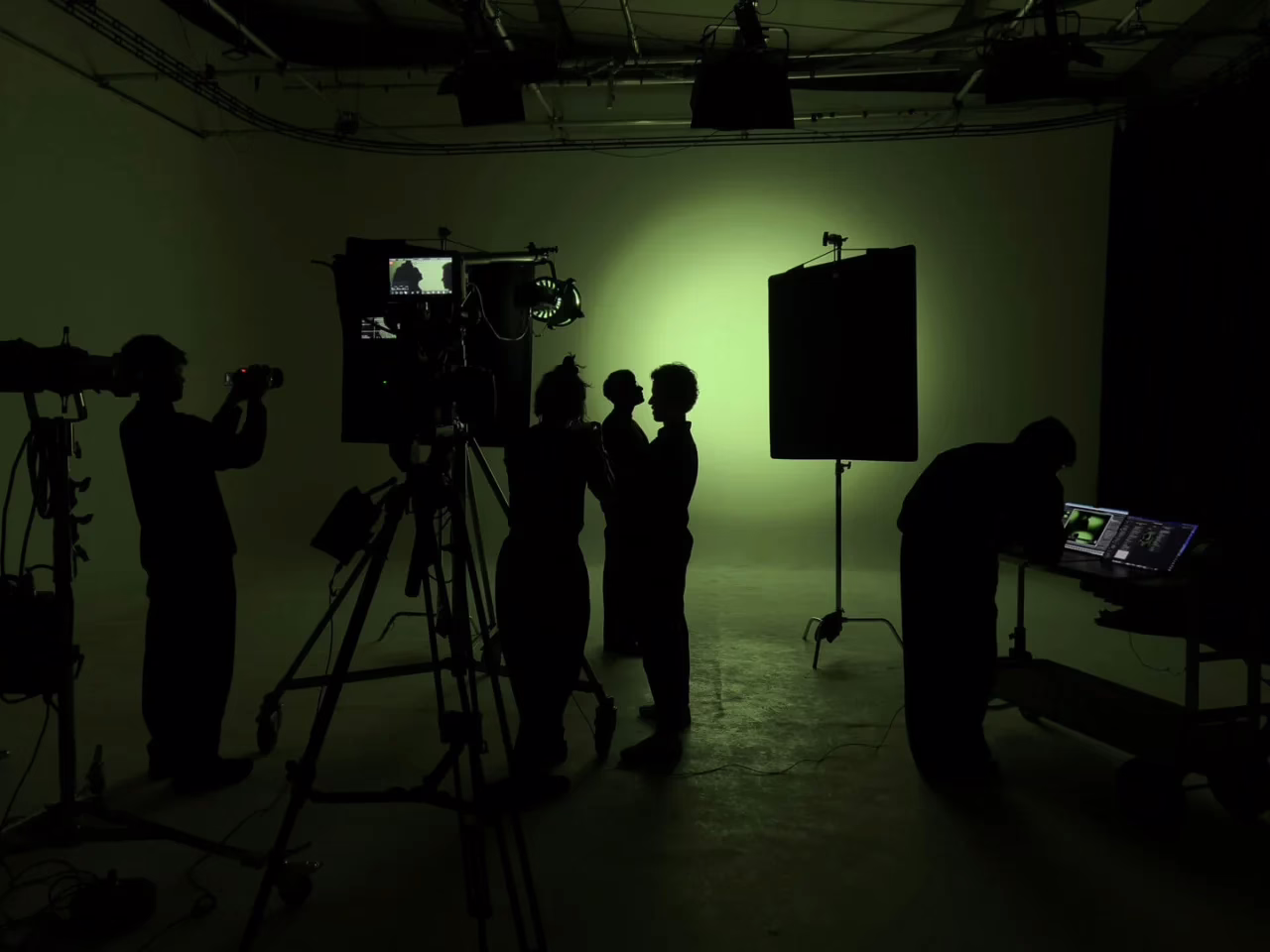 Film crew silhouetted around a cinema camera against a green-lit cove at Cineview Studios
