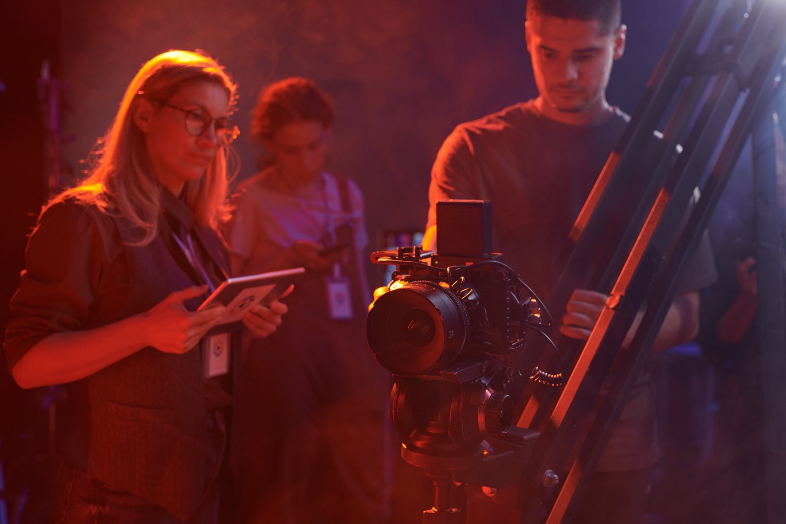 Film crew planning a camera setup together under coloured lighting
