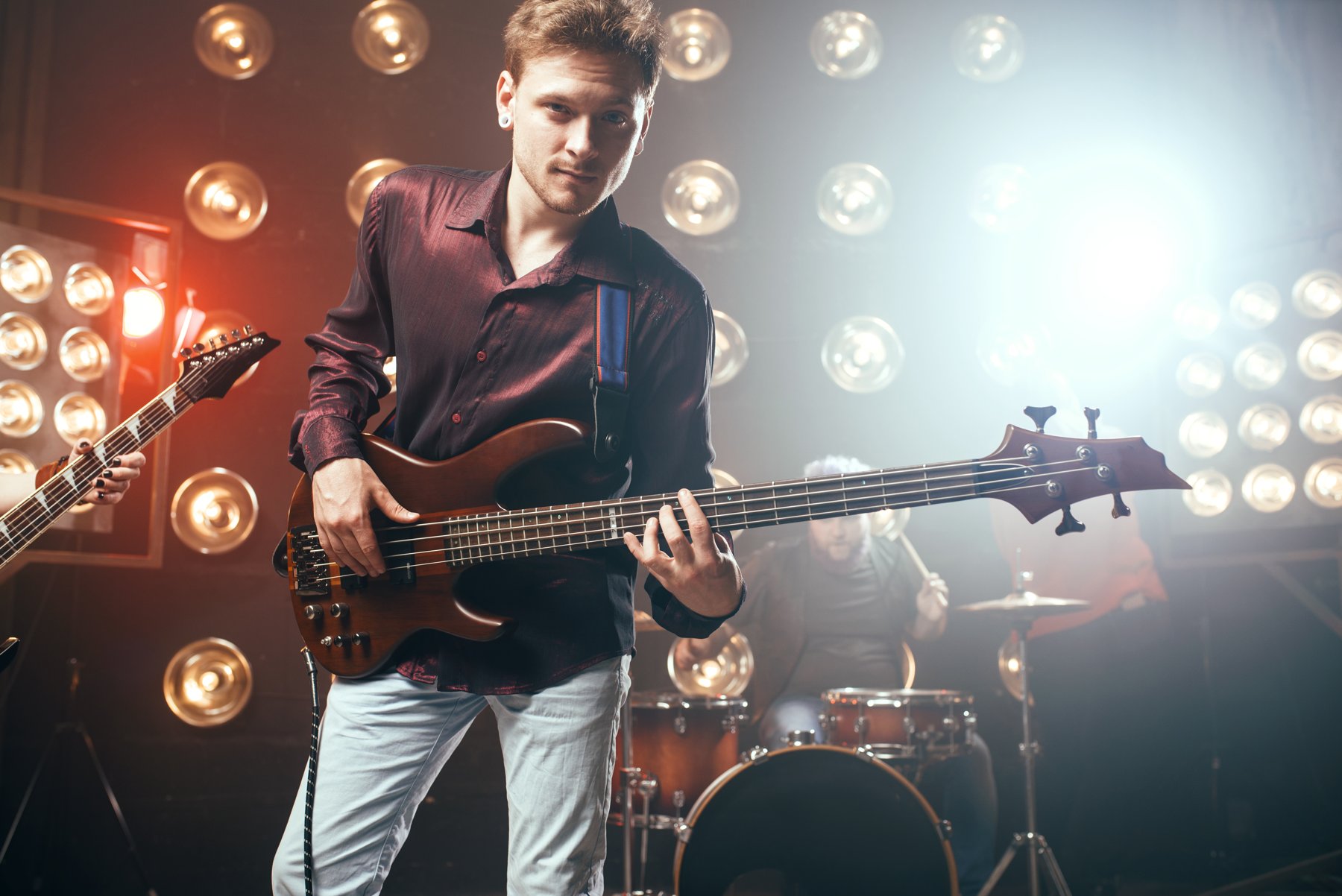 Bass guitarist performing under dramatic stage lights