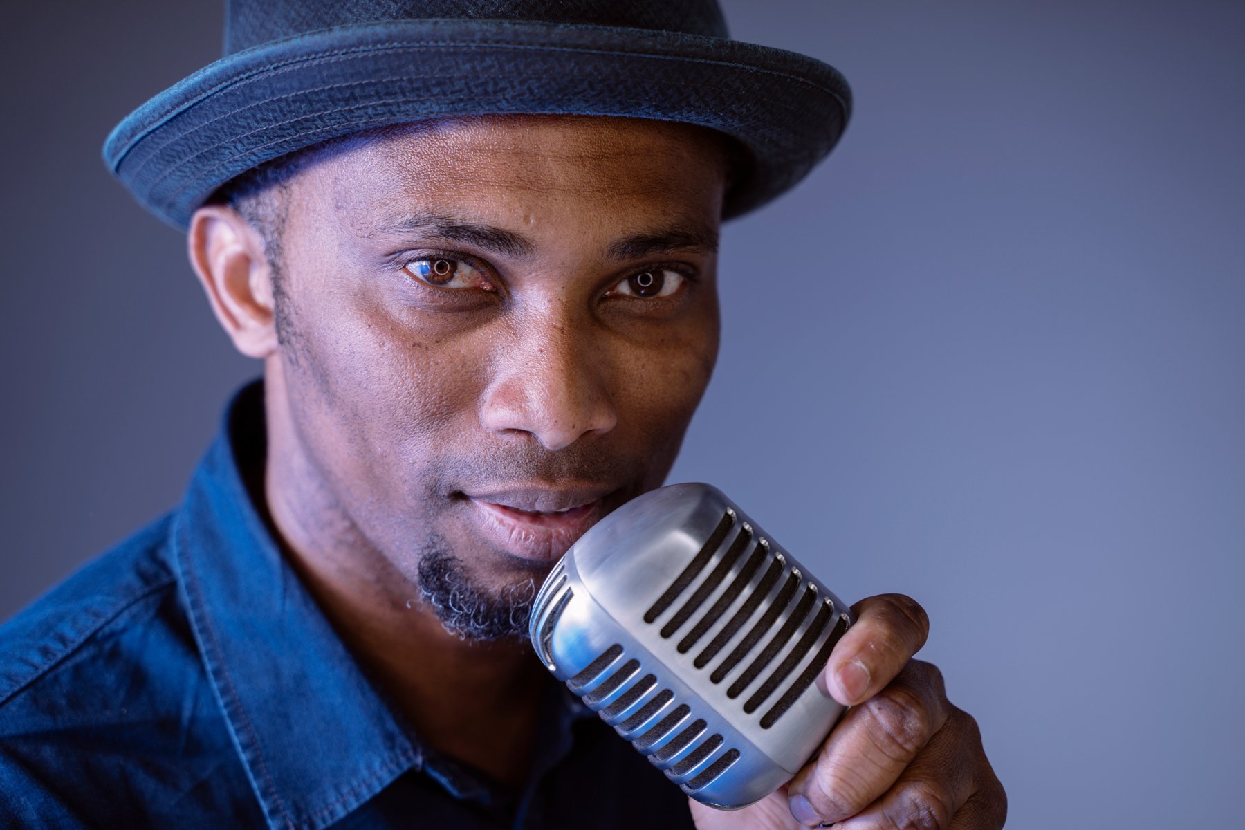 Artist portrait with a vintage microphone and hat