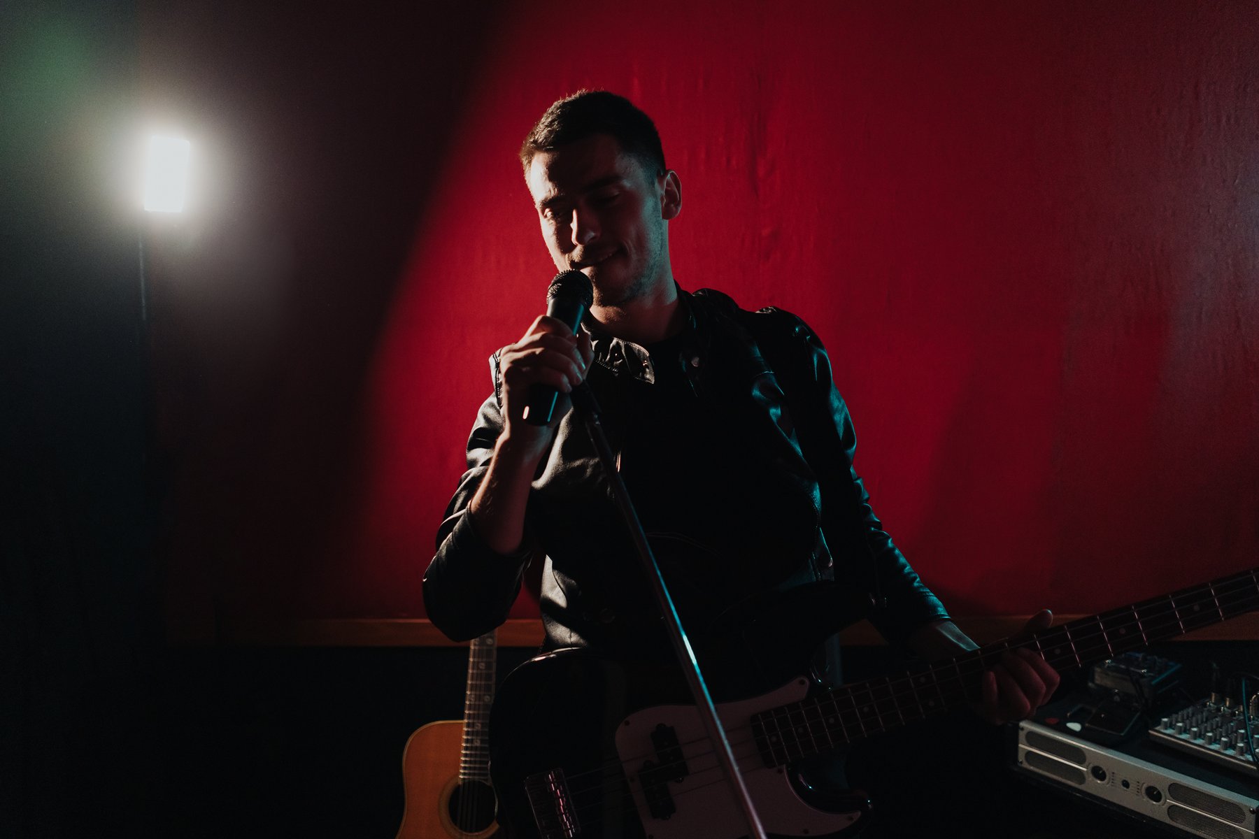 Guitarist and vocalist under red performance lighting