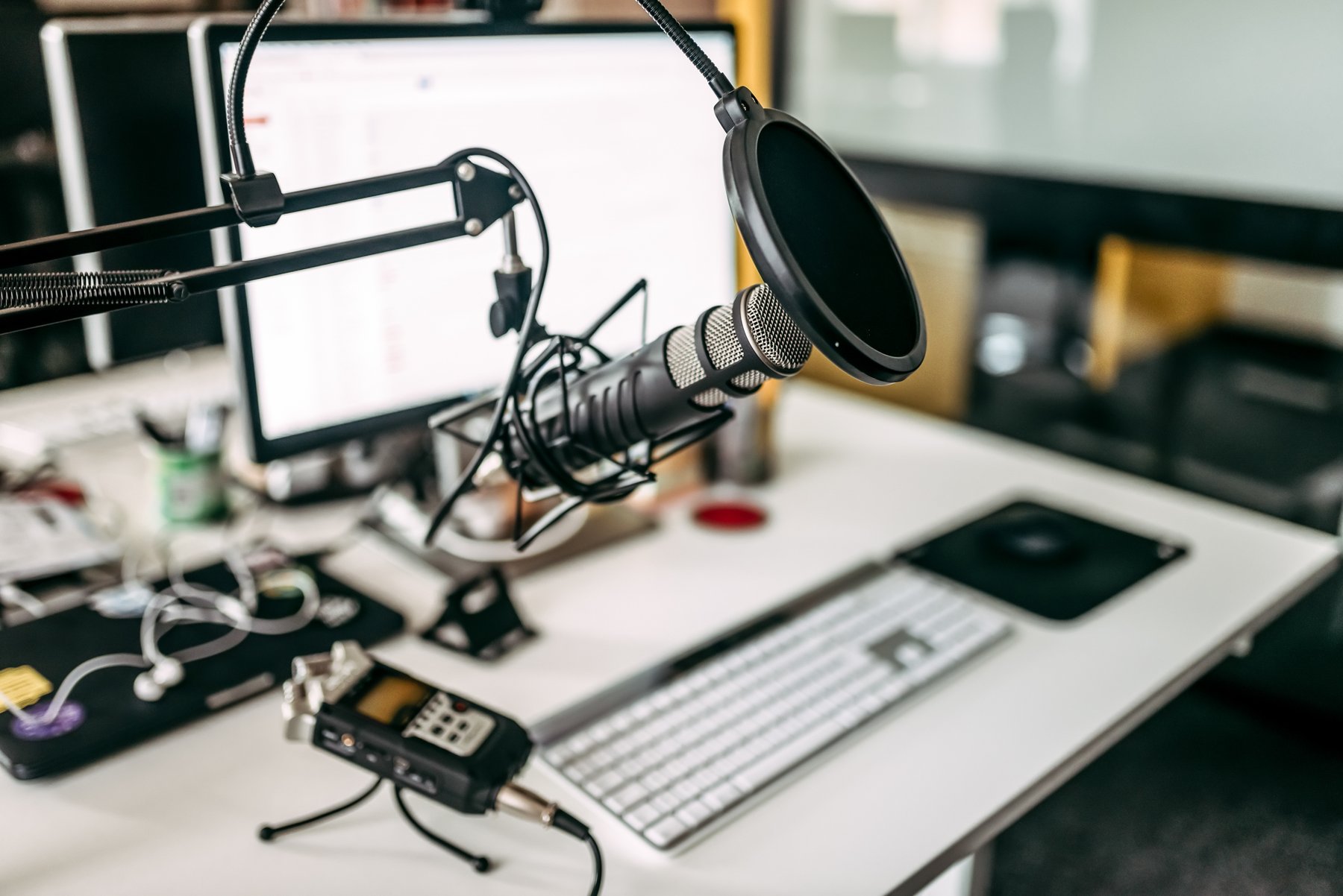 A recording microphone with a pop filter beside an audio workstation