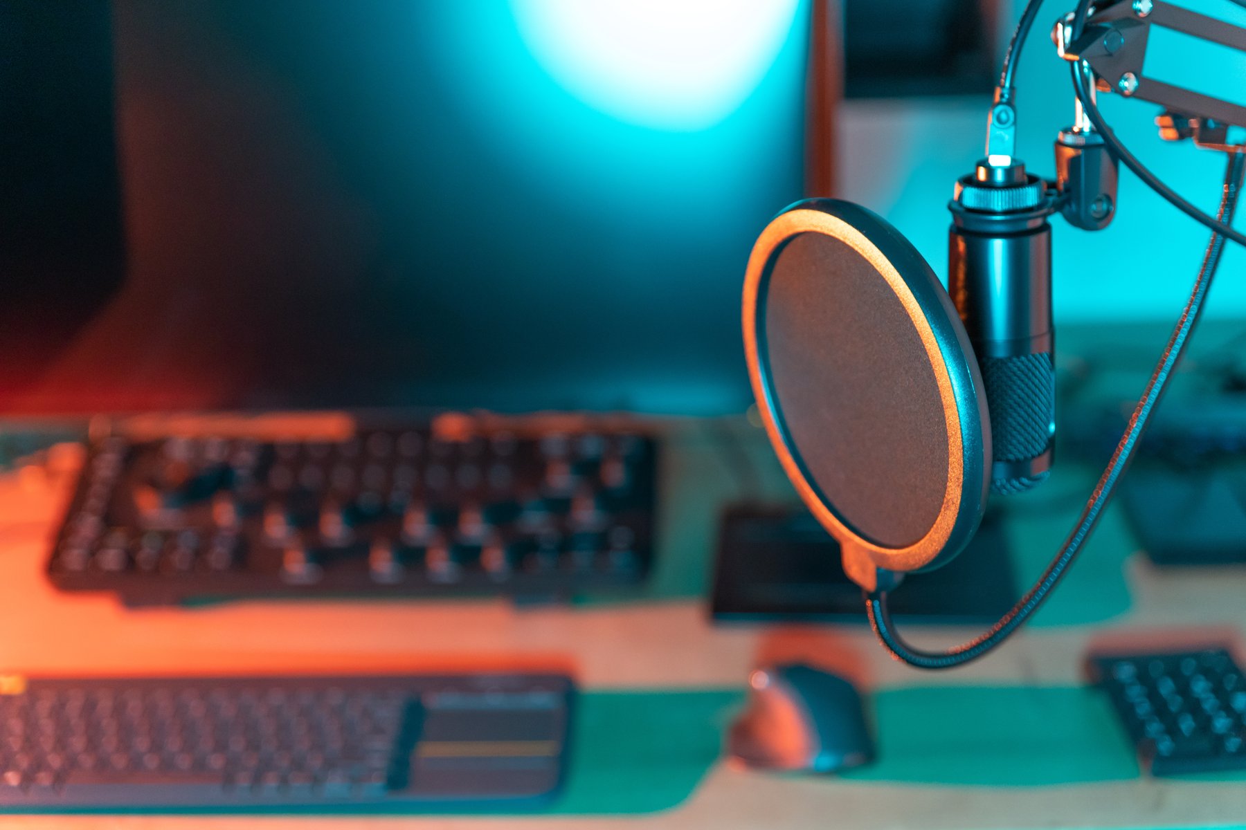 A podcast microphone and computer in a coloured recording setup