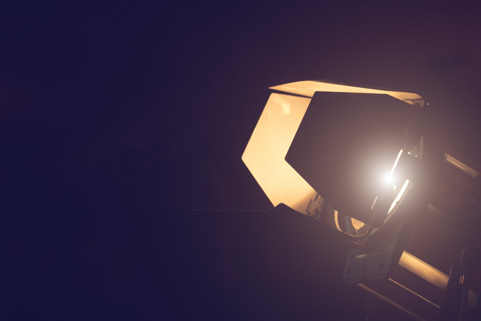 Film light with barn doors shining against a dark background