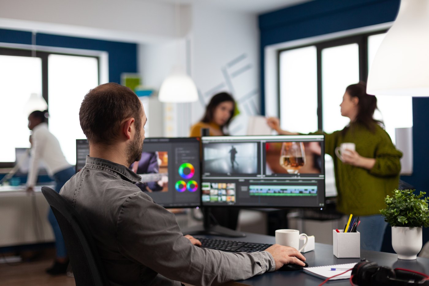 Video editor reviewing footage on two screens in an agency workspace