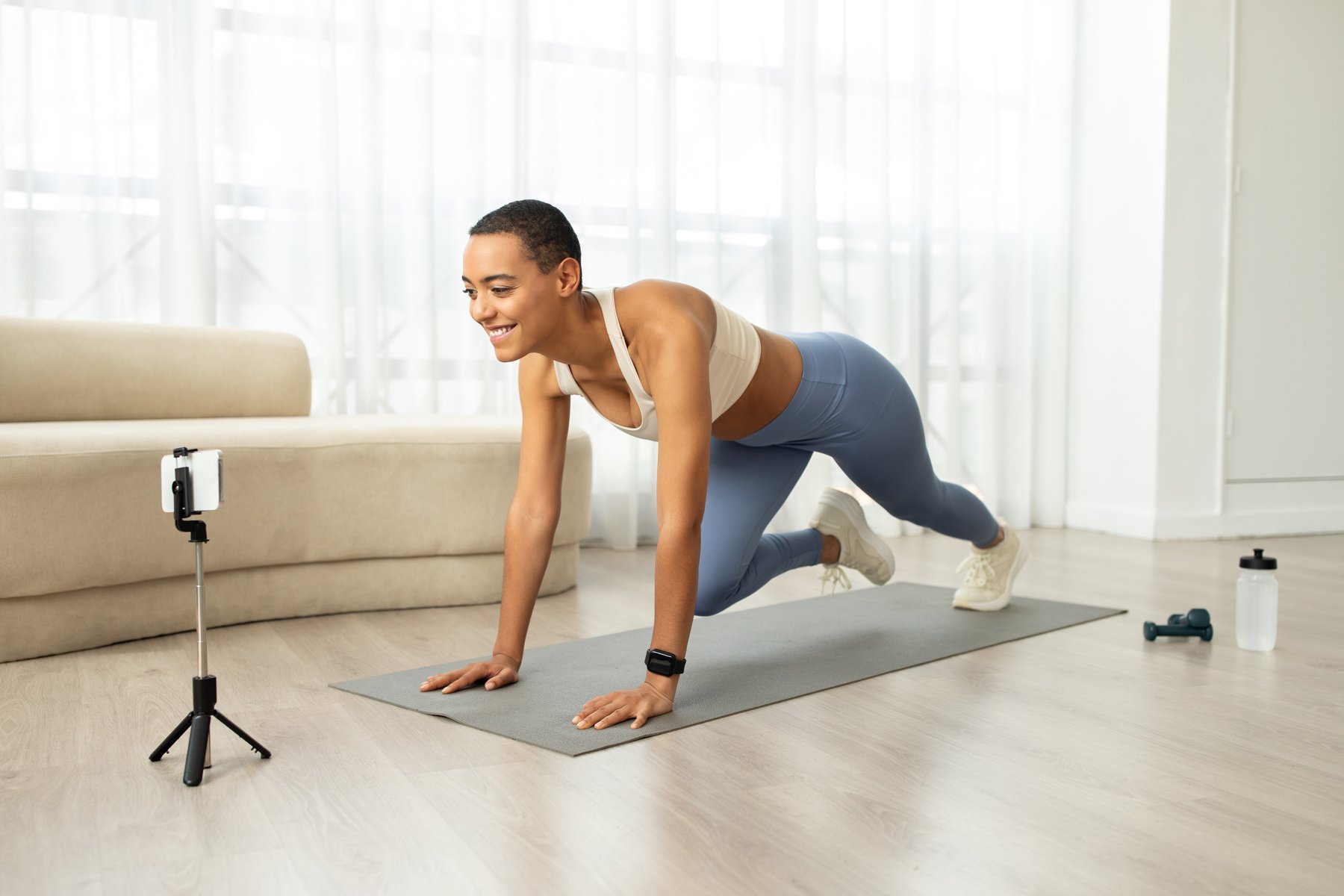 A fitness presenter recording a floor exercise on a phone