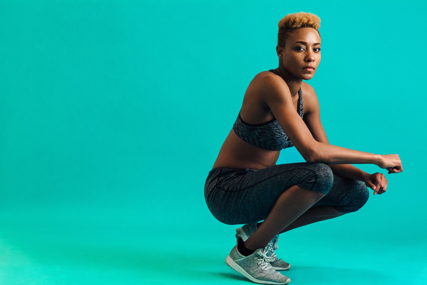 Athlete in activewear and trainers posed against a turquoise background