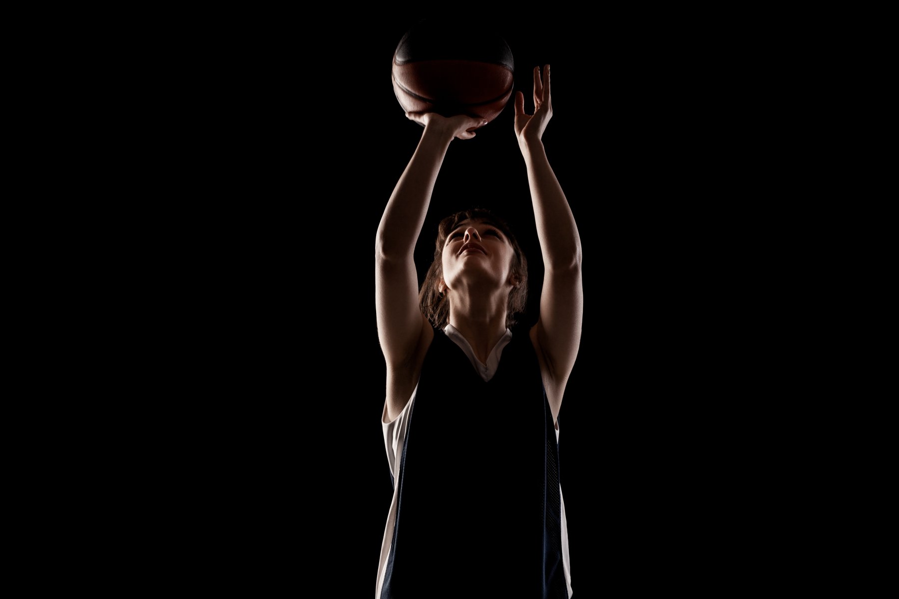 Basketball athlete preparing a shot against a dark background