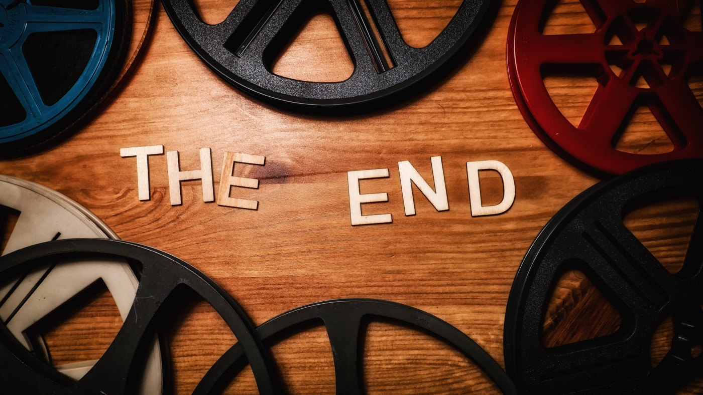 Wooden letters spelling The End beside film reels on a tabletop
