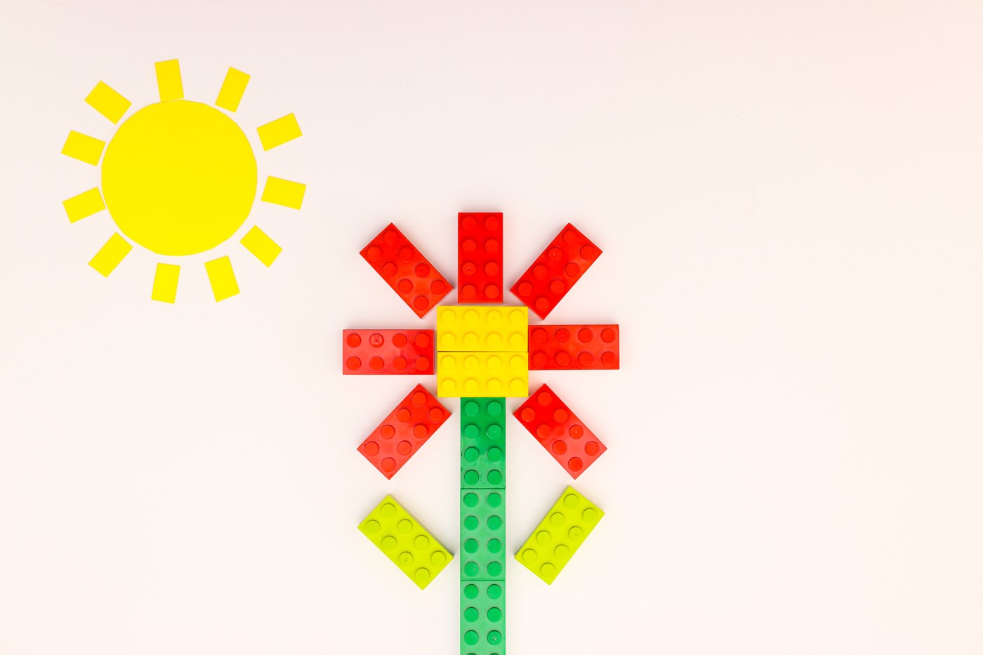 Small toy-brick flower and handmade sun arranged as a miniature scene