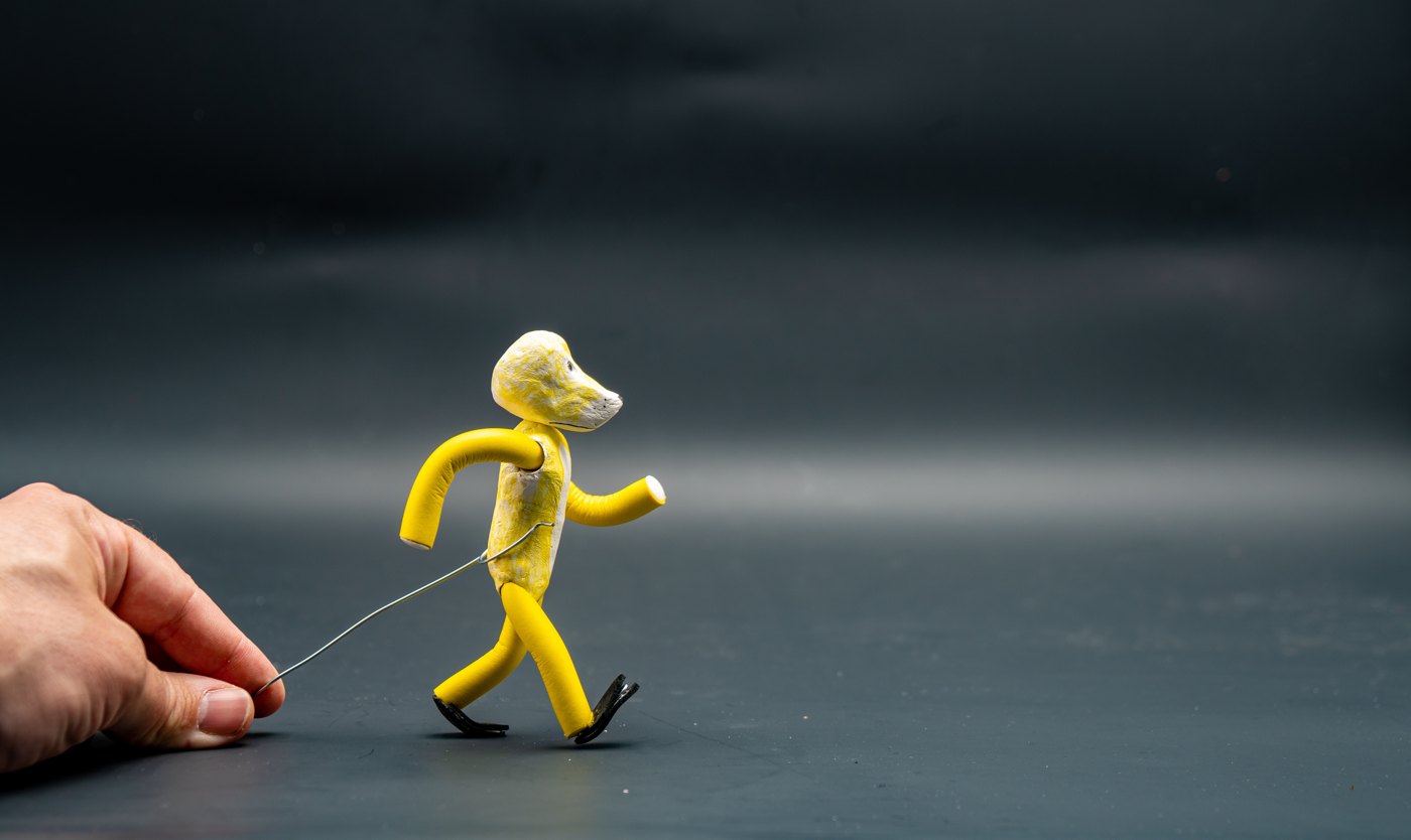 Hand adjusting a wire-supported clay character for stop motion animation